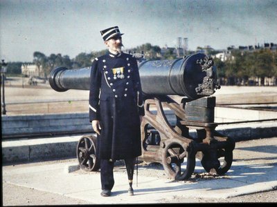 A Soldier in Uniform with Three Medals Standing Next to a Cannon in Paris, 1918 by Jules Gervais Courtellemont